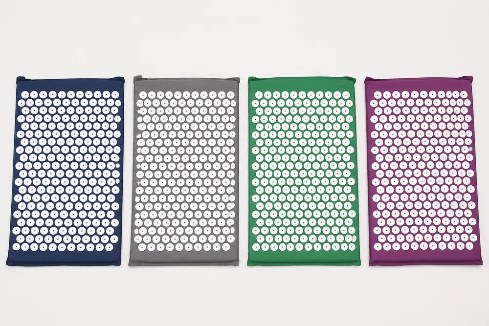 The four SpikeRest mat colours, navy, gray, green and purple, laid side by side on a plain backdrop