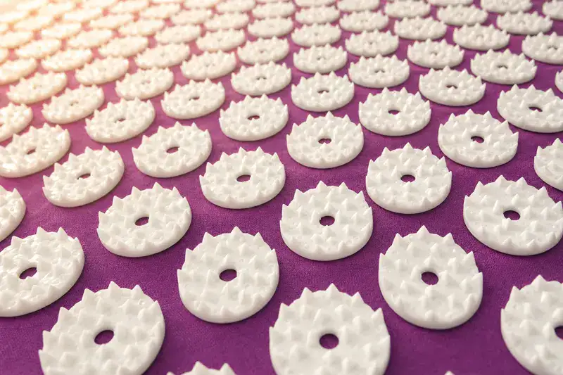 Close-up of the white plastic spike disks stitched onto a purple acupressure mat cover
