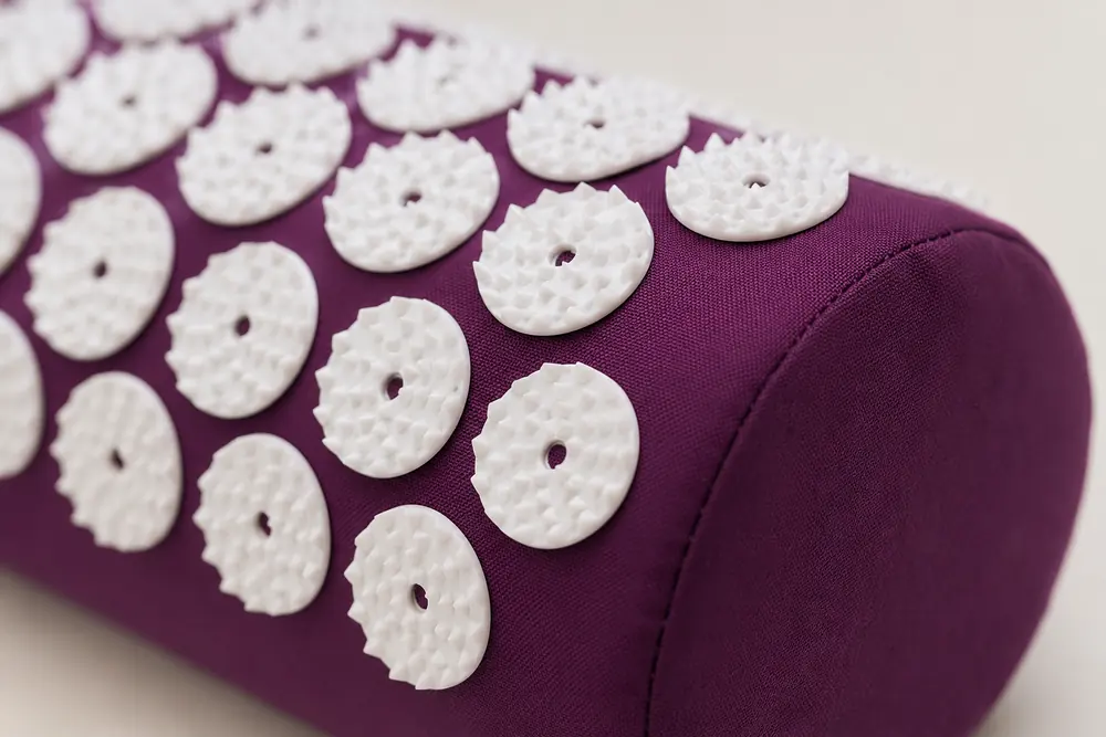 Macro view of the white spike disks on a purple bolster pillow, the half-cylinder curve visible