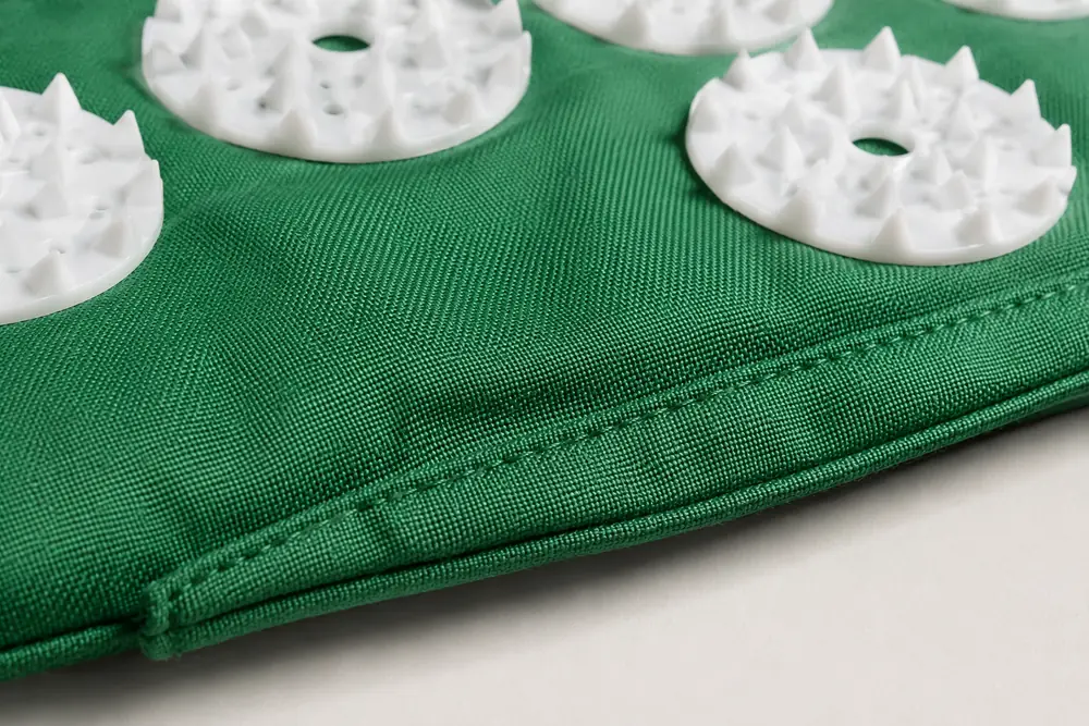 Extreme close view of the fabric edge and stitching of a green SpikeRest acupressure mat