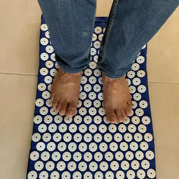 Buyer standing barefoot on the SpikeRest acupressure mat in Navy Blue