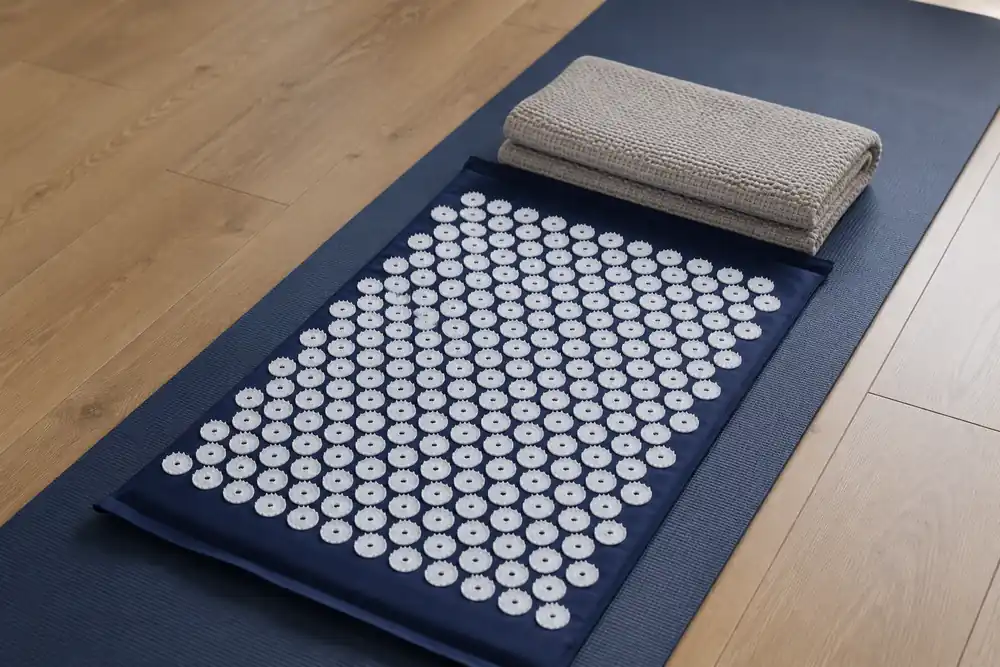 Navy acupressure mat on a yoga mat showing it covers from the neck to the lower back only